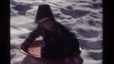 California USA (1981): Kid Slides Down Snowy Hill On A Red Lid Slides Into