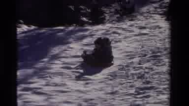 California USA (1981): Two Young Children In Coats Sled Down Bumpy Hill Sideways