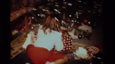 California USA (1984): Young Girl Opens Large Present While Crouching Next To