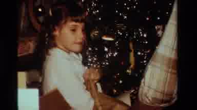 California USA (1984): Happy Curly Headed Child Unwraps Her Christmas Gifts