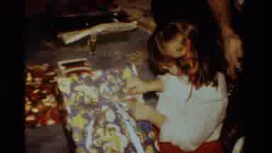 California USA (1984): Little Girl With Brown Hair Opens A Present On Camera