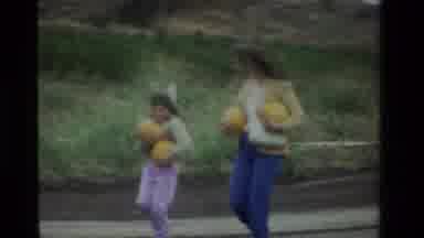 California USA (1984): Mother And Daughter Walking Side By Side Carrying Two