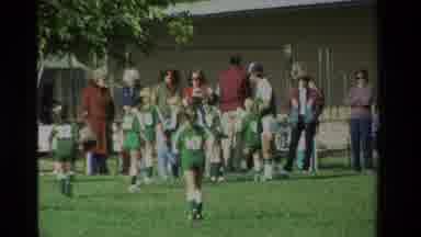 California USA (1984): Standing Child Cuts To Children In Sports Uniforms Running