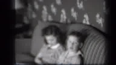 New York USA (1939): Siblings Sitting On A Couch Smiling For The Camera