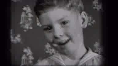 New York USA (1939): A Boy Standing In Front Of A Wall Covered In Wallpaper Smiles