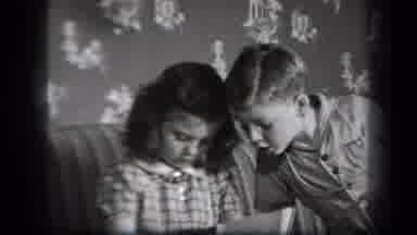 New York USA (1939): A Brother And Sister Are Sitting On A Couch Looking At A Book