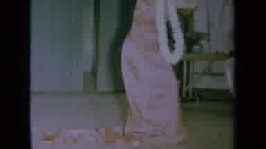 California USA (1961): Woman In A Long Pink Dress Doing A Dance With A White Lei