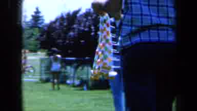 California USA (1961): Man Carries A Strip Of Lollipops As Another Group Of Men