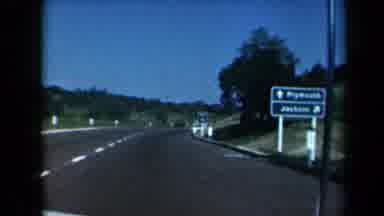 California USA (1969): Driver Negotiating A Corner On A Highway Full Of Signboards