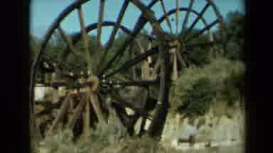 California USA (1969): Man Running Towards Two Extremely Large Wagon Wheels And
