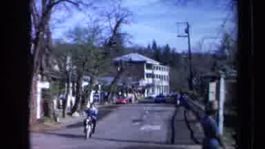 California USA (1969): Person Riding Bike Down A Road And Other People Shopping On