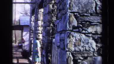 California USA (1969): A Woman Walking And Looking At An Old Man Made Building