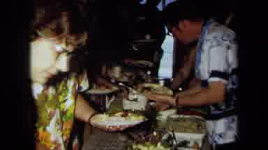 California USA (1971): Men And Women Wearing Colorful Leis Eating Food At Party