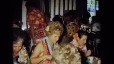 California USA (1971): Group Of People Wearing Hawaiian Clothing Sitting At Tables