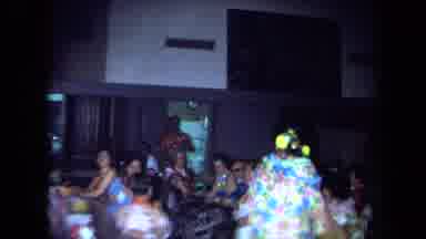 California USA (1971): A Lady In A Bright Shirt Standing Up In A Party With A