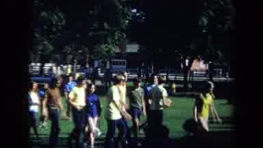 California USA (1971): Man Holding Child And Others Walking As A Group Together