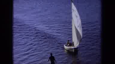 California USA (1971): A Small Personal Sailboat Approaches Shore And Lands