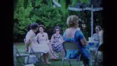 California USA (1971): A Group Of Women Are Sitting Around Under An Umbrella And