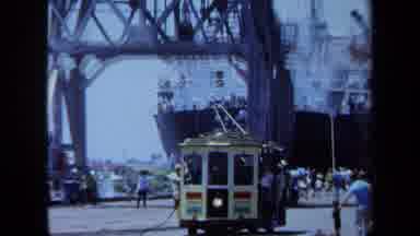 Maine USA (1971): Trolly Driving Down A Street Alongside A Pier With A Ship
