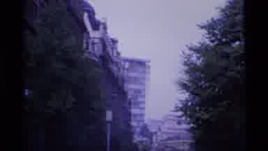 London England (1969): Couple Crossing A Street With Car And Close-Up Of Building
