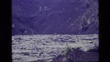 Idaho USA (1972): A Zoomed Out Shot Of A Shimmering Lake With Green Grassy Hills