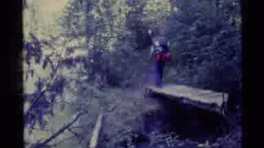 Alaska USA (1977): People Hiking Over A Bridge On To A Path Through The Woods On