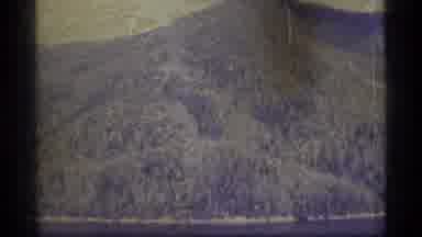 Alaska USA (1977): Tall Mountain With Trees And Man Sitting At Small Campsite