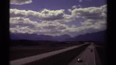 Canada (1979): Cars Driving On Highway Towards Mountains On A Cloudy Day
