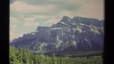Canada (1979): Green Trees With Large White And Gray Mountains In The Background