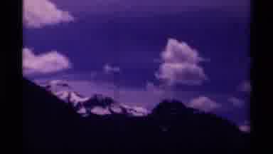 Canada (1979): Building Pans Over To Snow Peaked Mountains With Blue Skies And