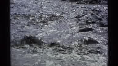 Alaska USA (1977): Backpacker Crossing A Muddy And Rocky Stream Watching His