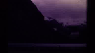 Canada (1979): People Walking Beside Trees Lake And Snowy Mountain On Cloudy Day
