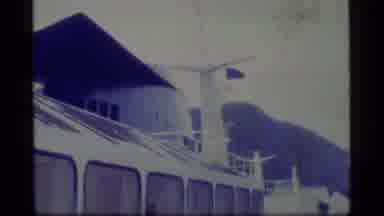 Alaska USA (1977): Ship With Flag Docked In Sea Near Mountainous Green Region