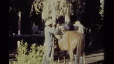 British Columbia Canada (1979): Man In Hat Saddles Closes Saddlebag As Second Man