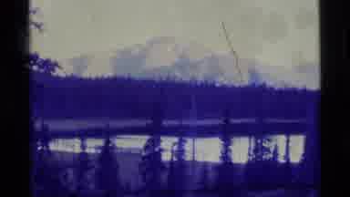 Alaska USA (1977): A Still Shot Of A Lake In The Woods Surrounded By Snow Capped