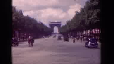 Paris France (1939): Cars And Bikes Riding Down The Road While People Stand In Amd