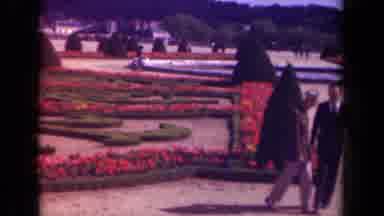 Paris France-1939: Two People Walking Through A Formal Garden With Red Flowers