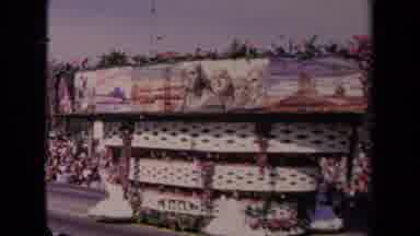 Los Angeles California USA (1967): Huge Parade Float Drives By As Woman On It Wave
