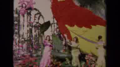 Los Angeles California USA-1967: Three Women In Pastel Gowns Wave From Floral Parrot Parade Float