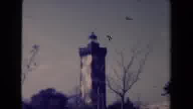France (1945): Man Riding A Bicycle On A Road Passing By Building And A Tower