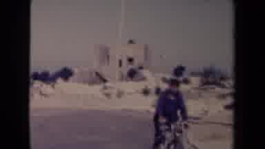 France (1945): Man Riding Bicycle In Desert Near A Church Like Building