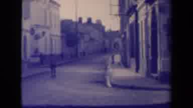 France (1945): Quiet Street Lined With Storefronts And People Walking Across A