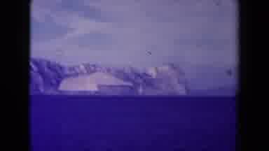 France (1945): Smoking Shipping Boat Roams Through The Cold Ocean By A Glacier On