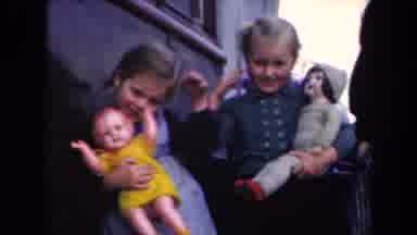 Netherlands (1946): Waving Happy Smiling Kids Holding Dolls Outside Building