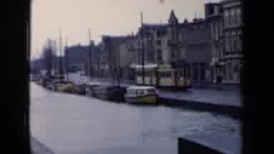 Netherlands (1946): An Antique Looking Bus Drives Past Historic Looking Buildings