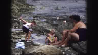 KANSAS CITY MISSOURI-1959: Mother Watches Two Children Play In The Puddles On