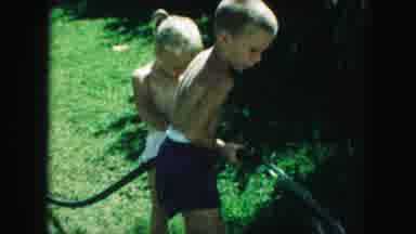 Kansas City Missouri (1959): Two Young Children Taking Turns Using A Hose To Water