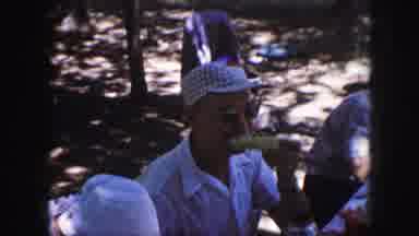 Kansas City Missouri (1959): Man Eating Corn While Playing With Baby Laying On A