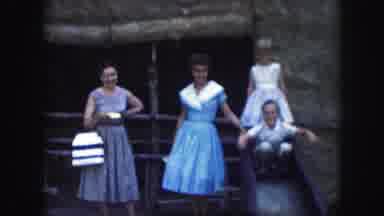 Kansas City Missouri (1959): Women In Dresses Watch Young Boy Wave Hands On Slide