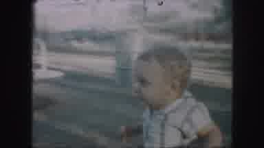 Kansas City Missouri (1959): Infant Walking In A Park By A Merry Go Round